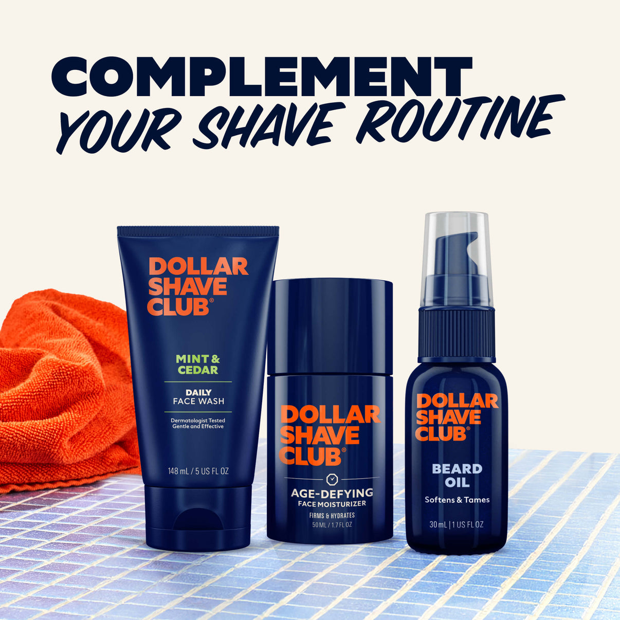 Dollar Shave Club grooming products including face wash, moisturizer, and beard oil on a checkered surface with an orange towel.