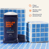 Dollar Shave Club deodorant stick on a tiled surface with product features listed.