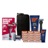 Dollar Shave Club University of Arkansas grooming kit on a white background. Includes a cardinal red razor handle with the Arkansas Razorbacks logo, 24 blades, Shave Butter, Prep Scrub, a black 3-in-1 electric trimmer, and a black traveler case.